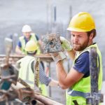 Un manoeuvre en construction soulève une armature
