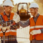 Deux travailleurs de la construction sans diplôme se serrent la main sur un chantier.